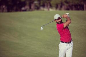 Golfspieler, der einen Sandbunkerschlag schlägt foto