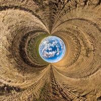 Blauer Himmelsball inmitten einer wirbelnden Asphaltstraße oder eines Feldes. Umkehrung der winzigen Planetentransformation des sphärischen Panoramas 360 Grad. sphärische abstrakte Ansicht. Krümmung des Raumes. foto