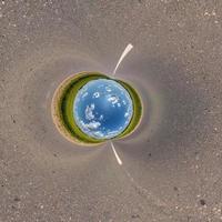 Blauer Himmelsball inmitten einer wirbelnden Asphaltstraße oder eines Feldes. Umkehrung der winzigen Planetentransformation des sphärischen Panoramas 360 Grad. sphärische abstrakte Ansicht. Krümmung des Raumes. foto