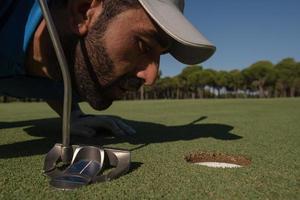 Golfspieler bläst Ball ins Loch foto