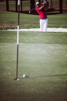 Golfspieler, der einen Sandbunkerschlag schlägt foto