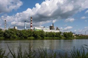 Rohre des Sägewerks des Holzbearbeitungsunternehmens in der Nähe des Flusses. Luftverschmutzungskonzept. Industrielandschaft Umweltverschmutzung Abfall von Wärmekraftwerken foto