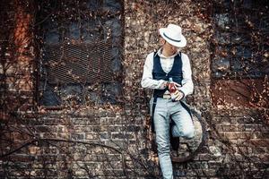 Fedora-Stil Mann mit Bierflasche gegen Mauer. foto