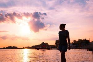 frau, die am strand steht und den wunderschönen sonnenuntergang genießt. foto