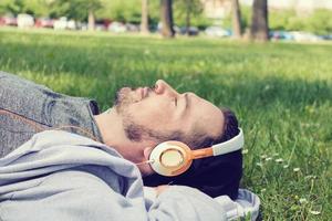 Ruhen im Frühlingsgras mit Musik über Kopfhörer. foto