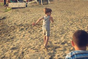 Rückansicht von verspielten Jungen, die auf dem Sand laufen. foto