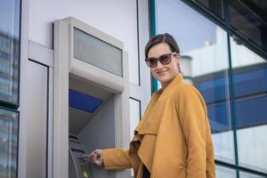Schöne Geschäftsfrau, die Geld vom Geldautomaten abhebt. foto