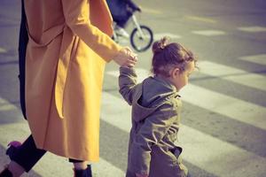 kleines Mädchen, das mit Mutter die Straße überquert. foto