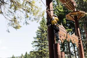 kleiner Junge befestigt Karabiner an Seilrutsche während der Canopy-Tour. foto