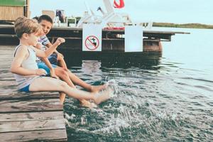 glückliche kinder, die wasser spritzen und spaß auf einem pier haben. foto