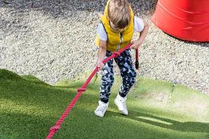 Oben Ansicht eines Jungen, der ein Seil hält, während er auf den Spielplatz klettert. foto