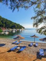 Unberührter Blick auf die Bucht einer griechischen Insel mit leeren Liegestühlen und Sonnenschirmen. foto