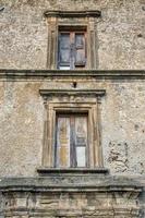 Nahaufnahme eines Holzrahmenfensters auf altem Haus in einem Dorf. Ein kleines Fenster und eine graue Stein- oder Backsteinmauer eines alten antiken Gebäudes in Italien. foto