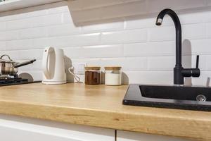 Schwarzes Wasserhahn-Waschbecken mit Wasserhahn und Seifenspender in teurer Loft-Küche foto