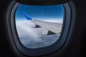 Flugzeugflügel aus dem Flugzeugfenster mit Blick auf den blauen Himmel und die schönen Wolken foto