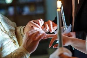 Der Pfarrer hilft den Jungvermählten beim Ringtausch bei der Trauung in der Kirche foto