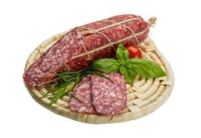 Salami auf Holzplatte und weißem Hintergrund foto