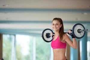 junge frau im fitnessstudio beim heben von gewichten foto