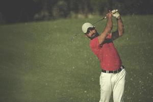 Golfspieler, der einen Sandbunkerschlag schlägt foto