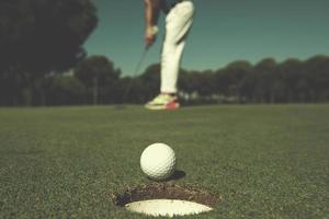 Golfspieler schlägt Schuss, Ball am Rand des Lochs foto