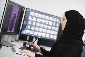 muslimische grafikdesignerin, die mit grafiktablett und zwei monitoren am computer arbeitet foto