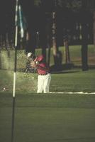 Golfspieler, der einen Sandbunkerschlag schlägt foto