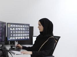 muslimische grafikdesignerin, die mit grafiktablett und zwei monitoren am computer arbeitet foto