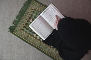 nahöstliche frau, die den heiligen koran betet und liest foto