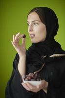 junges muslimisches mädchen, das traditionelle muslimische kleidung trägt und getrocknete datteln hält foto