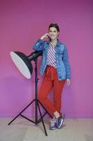 junge Frau, die sich gegen eine Studio-Taschenlampe über einem rosa Hintergrund lehnt foto