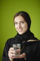 Nahöstliche Frau in Abaya mit einem Glas Wasser foto