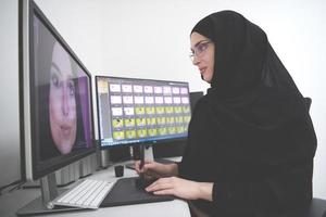 muslimische grafikdesignerin, die mit grafiktablett und zwei monitoren am computer arbeitet foto