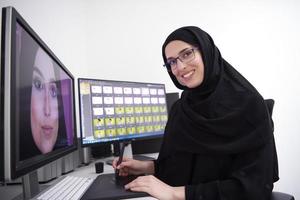 muslimische grafikdesignerin, die mit grafiktablett und zwei monitoren am computer arbeitet foto