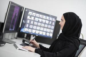 muslimische grafikdesignerin, die mit grafiktablett und zwei monitoren am computer arbeitet foto