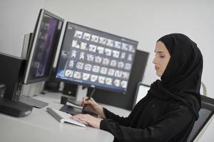 muslimische grafikdesignerin, die mit grafiktablett und zwei monitoren am computer arbeitet foto