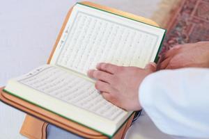 arabischer muslimischer mann, der zu hause den koran liest foto