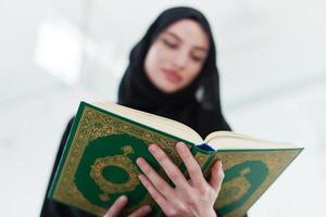 junge muslimische frau, die zu hause den koran liest foto