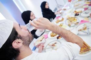 muslimische familie, die iftar-abendessen trinkt, um das fest zu brechen foto