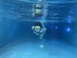 lächelndes Kind mit Brille schwimmen, mit Spaß im Pool tauchen - tief unter Wasser springen. gesunder lebensstil, menschen wassersportaktivitäten im sommer. foto