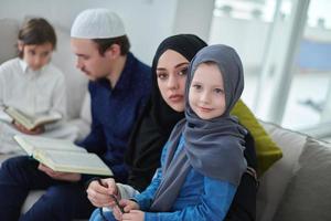 junge muslimische familie, die während des ramadan den koran liest foto