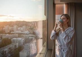 junge frau, die abendkaffee am fenster genießt foto