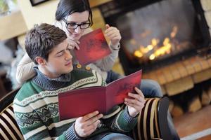 junges romantisches paar, das zu hause vor dem kamin sitzt und sich entspannt foto