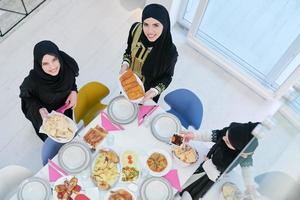 junge muslimische mädchen, die essen auf dem tisch für iftar-dinner draufsicht servieren foto