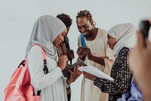 gruppe glücklicher afrikanischer studenten, die gespräche führen und teamtreffen, die gemeinsam an hausaufgaben arbeiten mädchen, die traditionelle sudanesische muslimische hijab-mode tragen foto