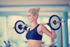 junge frau im fitnessstudio beim heben von gewichten foto