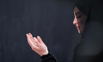 muslimische frau, die traditionelles beten zu gott vor schwarzer tafel macht foto