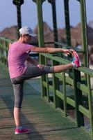 frau, die sich vor dem morgendlichen joggen dehnt foto