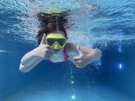 lächelndes Kind mit Brille schwimmen, mit Spaß im Pool tauchen - tief unter Wasser springen. gesunder lebensstil, menschen wassersportaktivitäten im sommer. foto