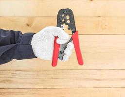 Hand im Handschuh halten Abisolierzange foto