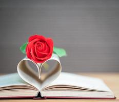Buchseiten gebogene Herzform und rote Rose foto